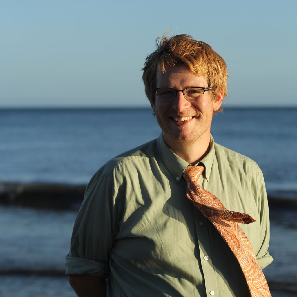 photo of Zach by the ocean, wearing an orange tie and a green shirt